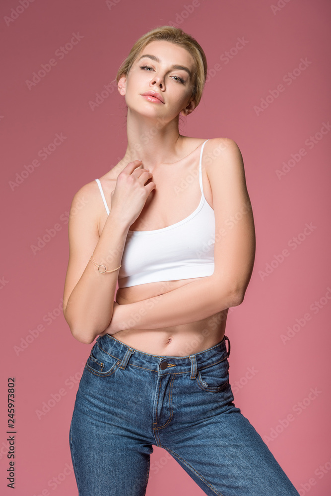 blonde slim woman posing in white bra, isolated on pink blonde slim woman posing in white bra, isolated on pink