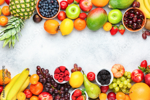 Fototapeta Naklejka Na Ścianę i Meble -  Healthy fruits berries background, strawberries raspberries oranges plums apples kiwis grapes blueberries mango persimmon on the white table, top view, copy space for text, selective focus