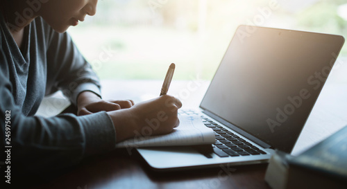 Young asia student study in the public library, She making note on notebook and using laptop.