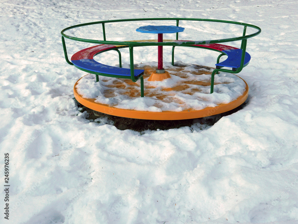 giostra colorata nel parco giochi per bambini sotto la neve in inverno  Stock Photo