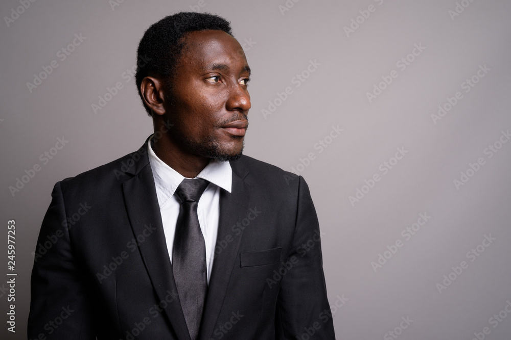 Young handsome African businessman against gray background Young handsome African businessman against gray background