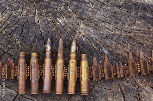 caliber bullet belt of the Second World War.  old rusted used steel ammo casings on a background of an old stump texture