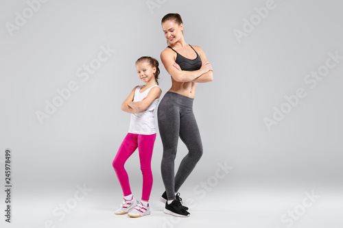 Sportive beautiful woman and her daughter posing on camera