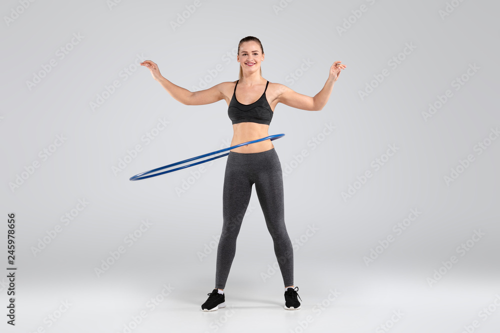 Beautiful woman doing exercises with hula hoop