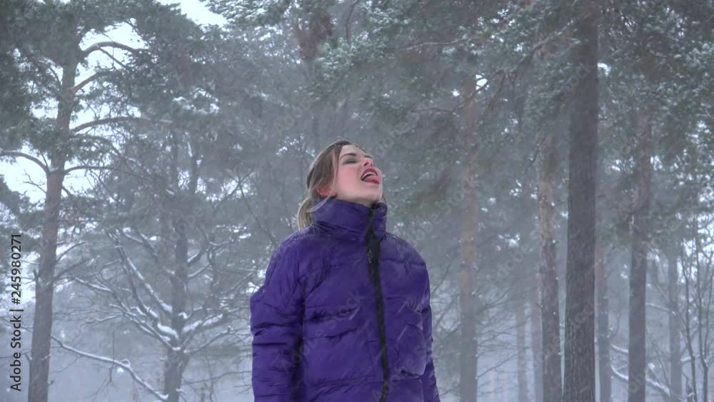 Girl rejoices in the snowfall and catches snowflakes by mouth at the winter forest. Girl rejoices in the snowfall and catches snowflakes by mouth at the winter forest.