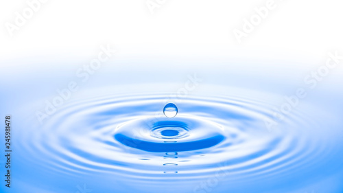 ein Wassertropfen fällt ins blaue Wasser, weißer Hintergrund