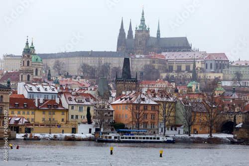 Snowy foggy Prague Lesser Town with gothic Castle above River Vltava, Czech republic