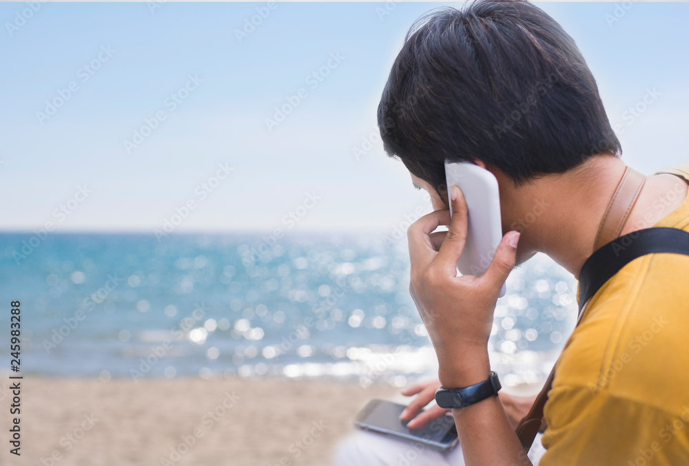 Freelane using phone on the beach, outside background, sunny day ,Young man tourist using smartphone sitting at the beach,copy space, Freelane using phone on the beach, outside background, sunny day ,Young man tourist using smartphone sitting at the beach,copy space,