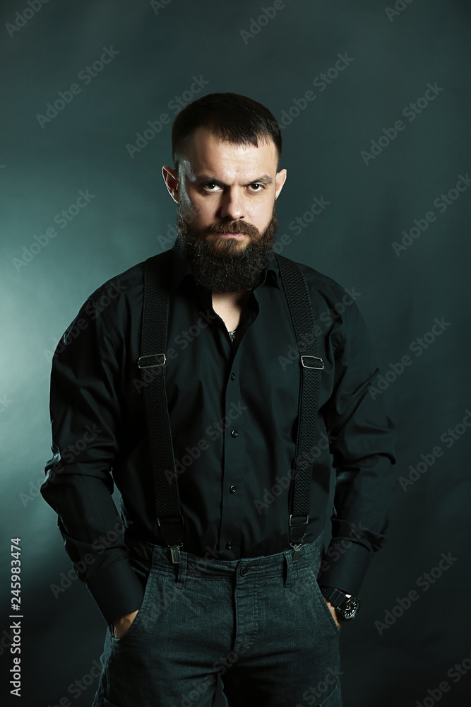 Obraz premium young handsome man with big beard in black t shirt on black background 