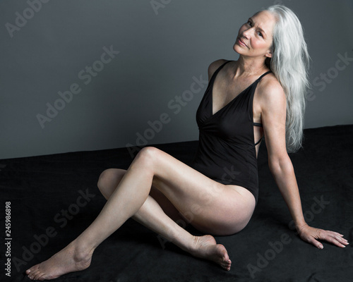 Portrait of smiling mature woman with gray hair sitting indoors