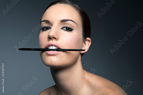 Portrait of young woman holding eyeliner in her mouth