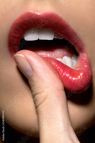 Close up of woman's thumb touching her red lips