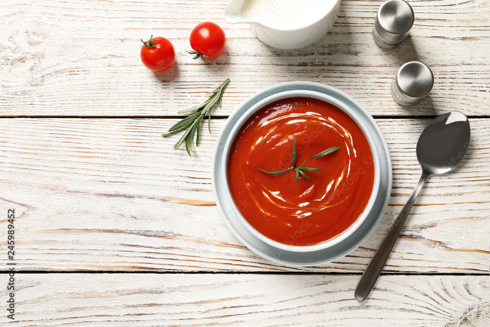 Bowl with fresh homemade tomato soup and space for text on wooden table, top view Bowl with fresh homemade tomato soup and space for text on wooden table, top view
