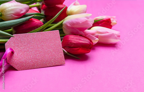 Tulips bouquet and blank tag on bright pink background, copy space, closeup view