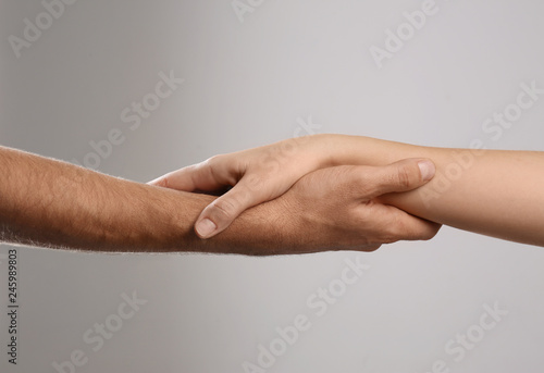 Man and woman holding hands on grey background, closeup. Help and support concept