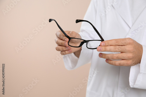 Male ophthalmologist with eyeglasses on light background, closeup. Space for text