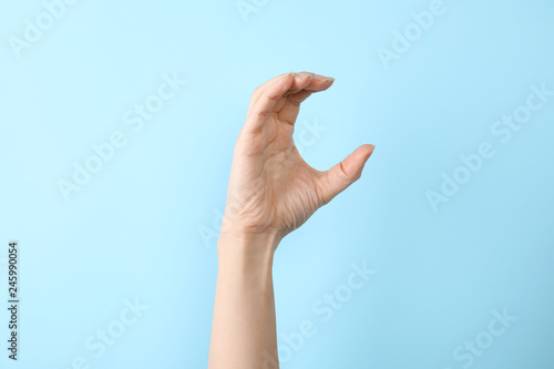 Woman showing C letter on color background, closeup. Sign language