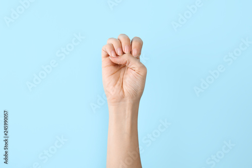 Woman showing E letter on color background, closeup. Sign language