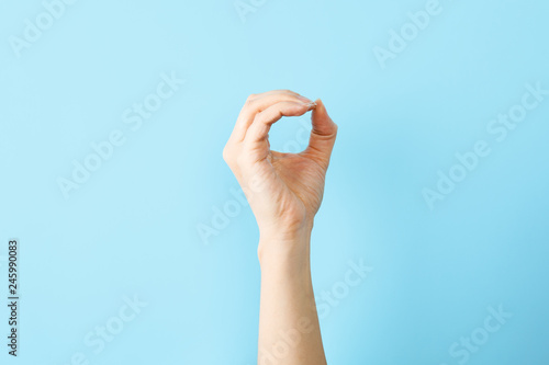 Woman showing O letter on color background, closeup. Sign language