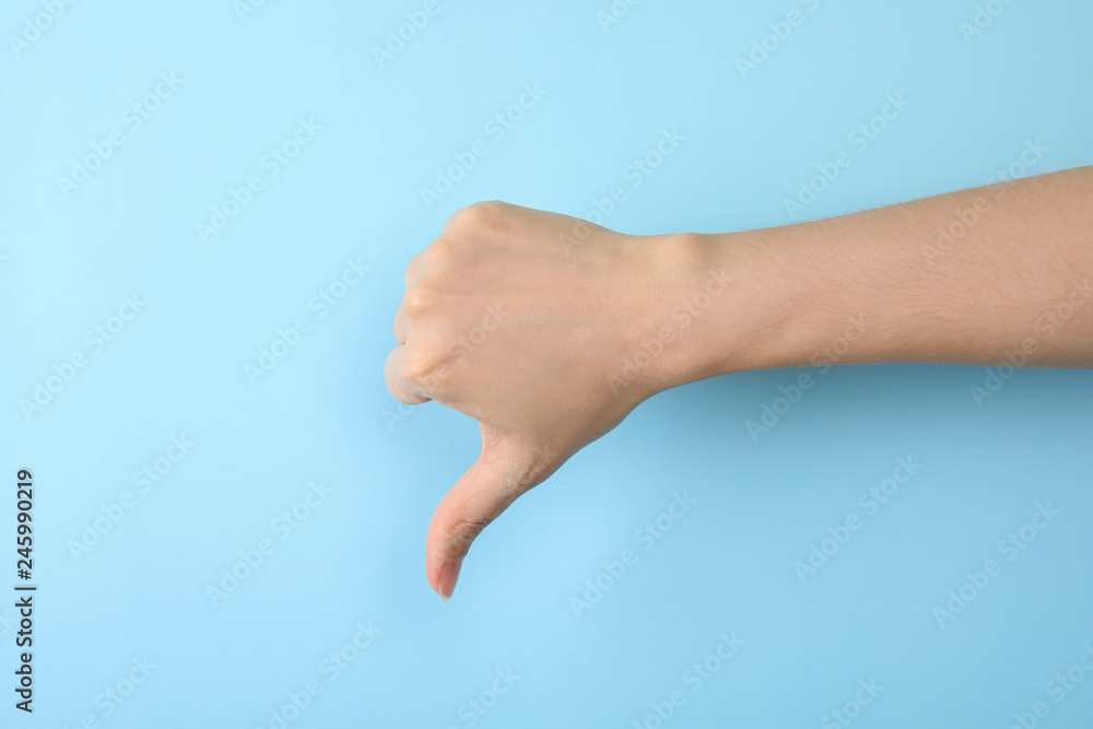 Woman showing thumb down sign on color background, closeup. Body language Woman showing thumb down sign on color background, closeup. Body language