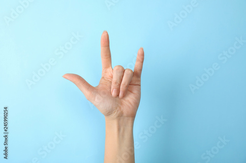 Woman showing hand sign on color background, closeup. Body language