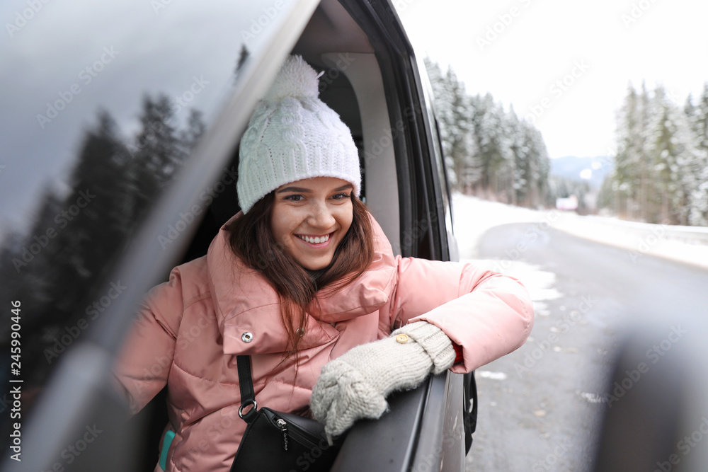 Young woman driving car and looking out of window on road. Winter vacation Young woman driving car and looking out of window on road. Winter vacation