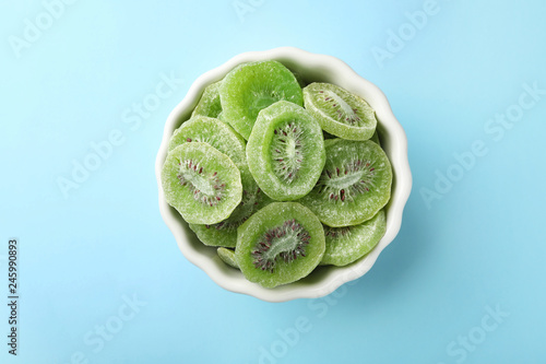 Bowl with slices of kiwi on color background, top view. Dried fruit as healthy food