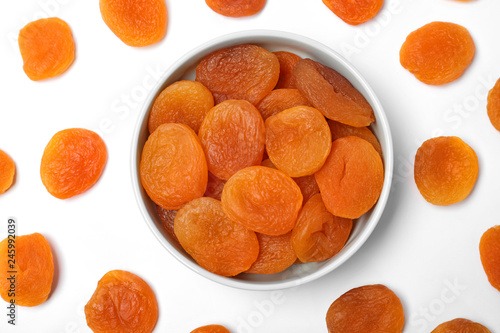 Flat lay composition with bowl of dried apricots on white background. Healthy fruit