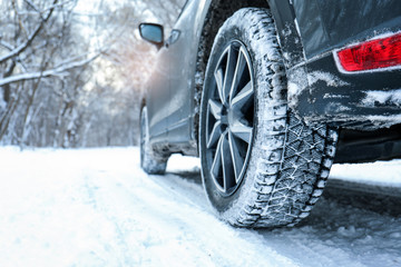 Snowy country road with car on winter day, closeup. Space for text