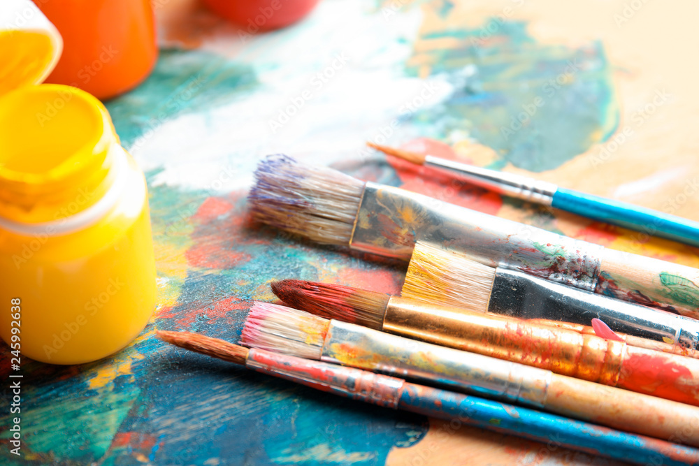 Obraz premium Different brushes and jars with paint on palette, closeup