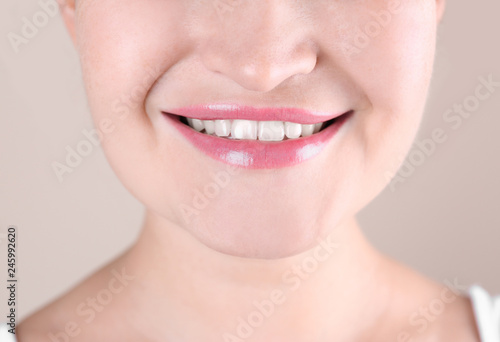 Young woman with beautiful smile on color background  closeup