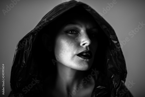 Emotive photo of a beautiful bald woman in a black raincoat with the hoods on.