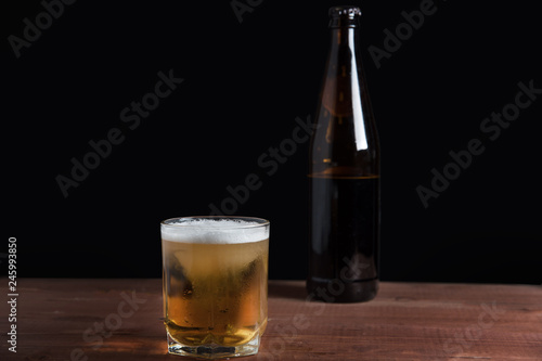 light beer with foam in a glass on a wooden table