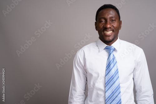Young handsome African businessman against gray background