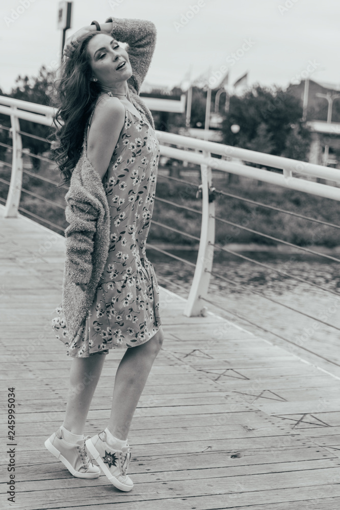 beautiful girl stands on the bridge, the wind blows in her face, developing her hair. girl smiles. dancing black and white photo. beautiful girl stands on the bridge, the wind blows in her face, developing her hair. girl smiles. dancing black and white photo.