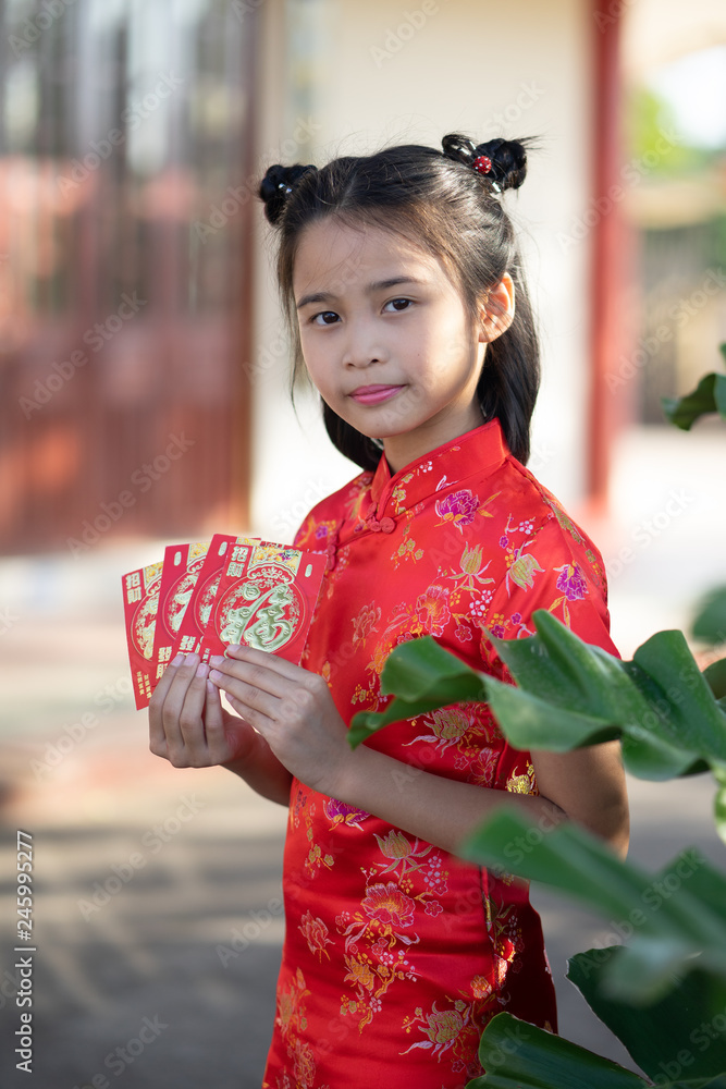 Chinese children in traditional costume holding red packet of money and smiling. Chinese children in traditional costume holding red packet of money and smiling.