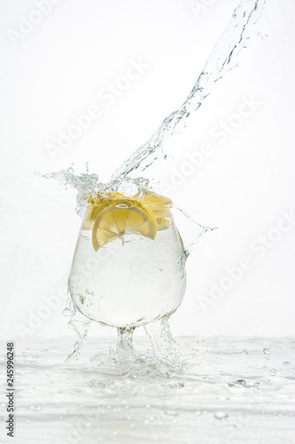 Water pours into a glass with lemon