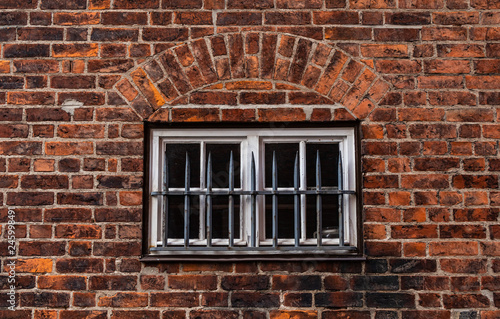 Vergittertes Fenster an einem Backsteinhaus