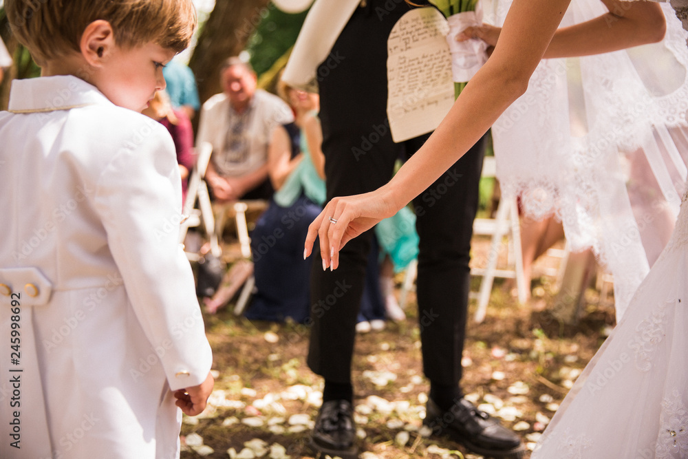 Naklejka premium Close-up the bride giving a hand to little boy outdoor