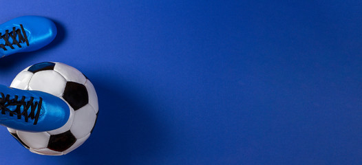 Soccer ball under soccer players feet on blue background