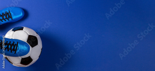 Fototapeta Naklejka Na Ścianę i Meble -  Soccer ball under soccer players feet on blue background
