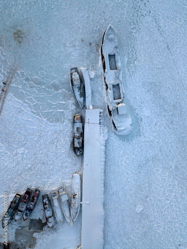 Aerial photo of frozen ship in ice of Lake Baikal. There is snow everywhere.