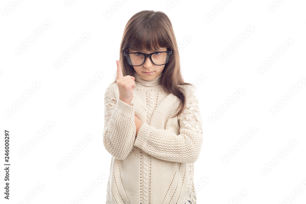 Portrait of a serious little girl of 7 years old. Sad girl in glasses shows fingers up.