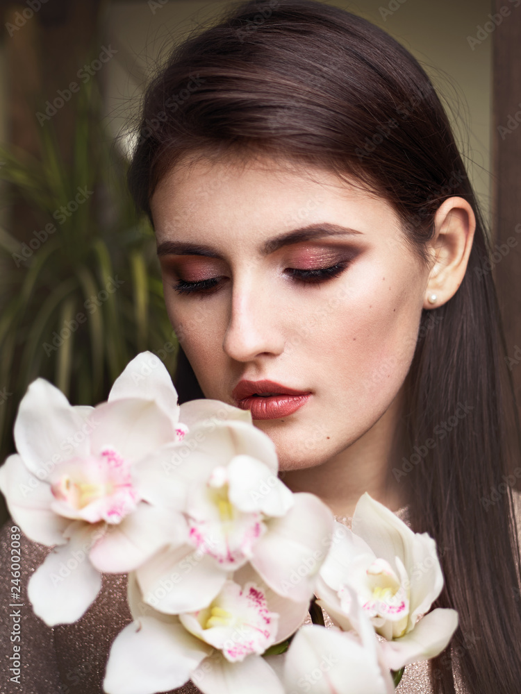 Young beautiful brunette business woman florist holding orchid branch of fresh flowers in flower shop Young beautiful brunette business woman florist holding orchid branch of fresh flowers in flower shop