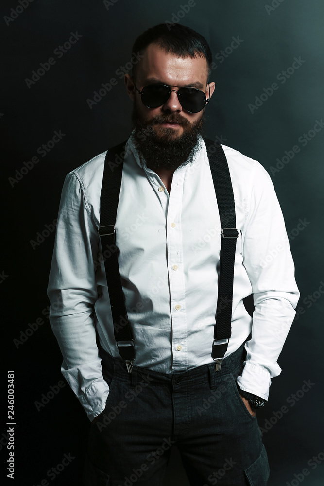 young handsome man with big beard and black sunglasses on black background young handsome man with big beard and black sunglasses on black background