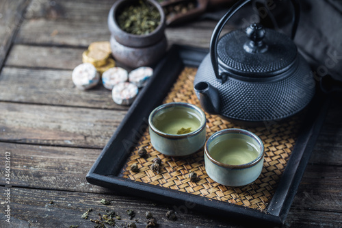 Fotografie Still-life of japanese healthy green tea in a small cups and teapot over dark ba