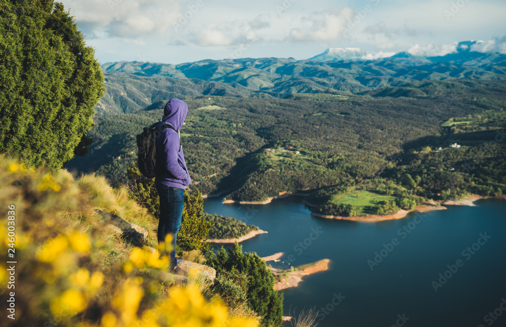 tourist traveler with backpack on top mountain and enjoys river, hiker relax looking on blue sky clouds, background nature panoramic landscape in trip, holiday mockup concept in trekking trip