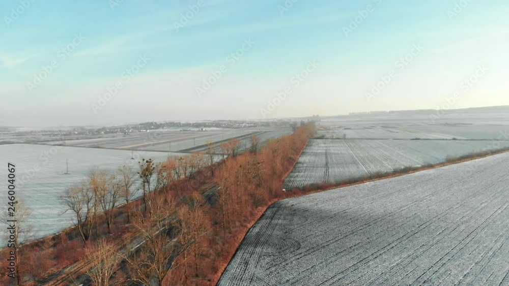 Aerial view of the road in the magnificent large fields in the countryside on sunny winter morning. Travel with drone.