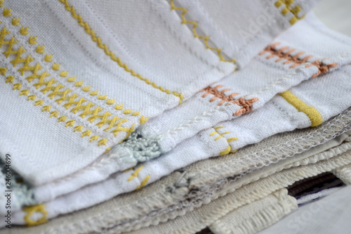 Different yellow, orange and blue patterns of embroidery on white and gray fabric