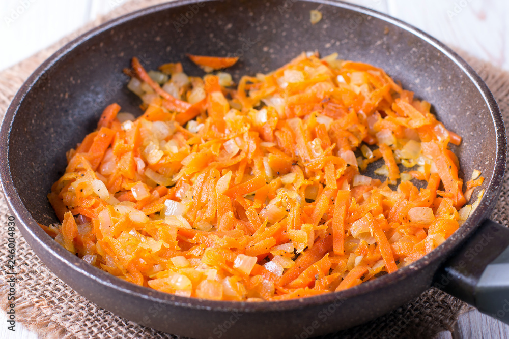 onion rings and carrots stew in a hot pan, close-up